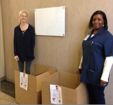 Two women standing next to boxes to fill with donations